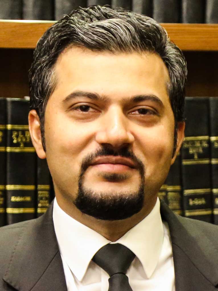 Lawyer posing confidently in front of legal books in a law office setting.