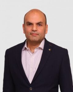 Legal professional in a dark suit with a light shirt, posing against a plain background.