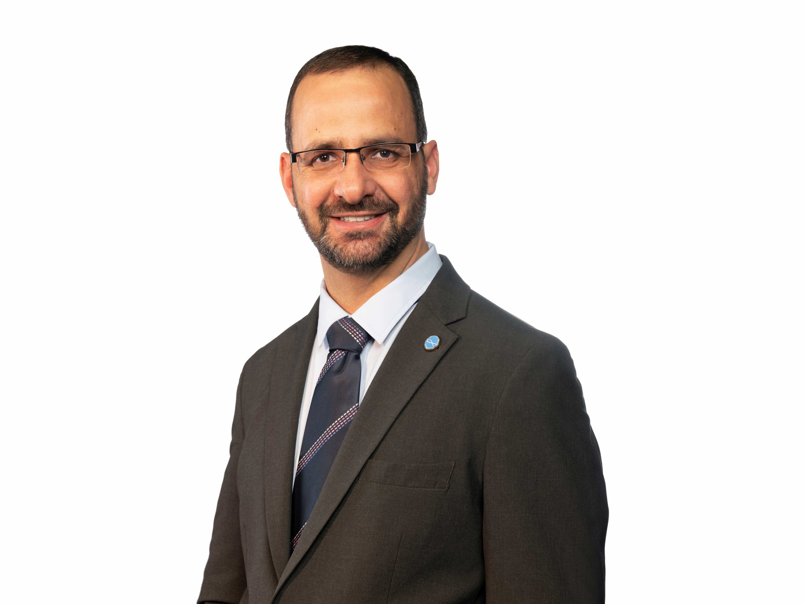 Lawyer in a suit smiling, standing against a white background, showcasing a professional appearance.
