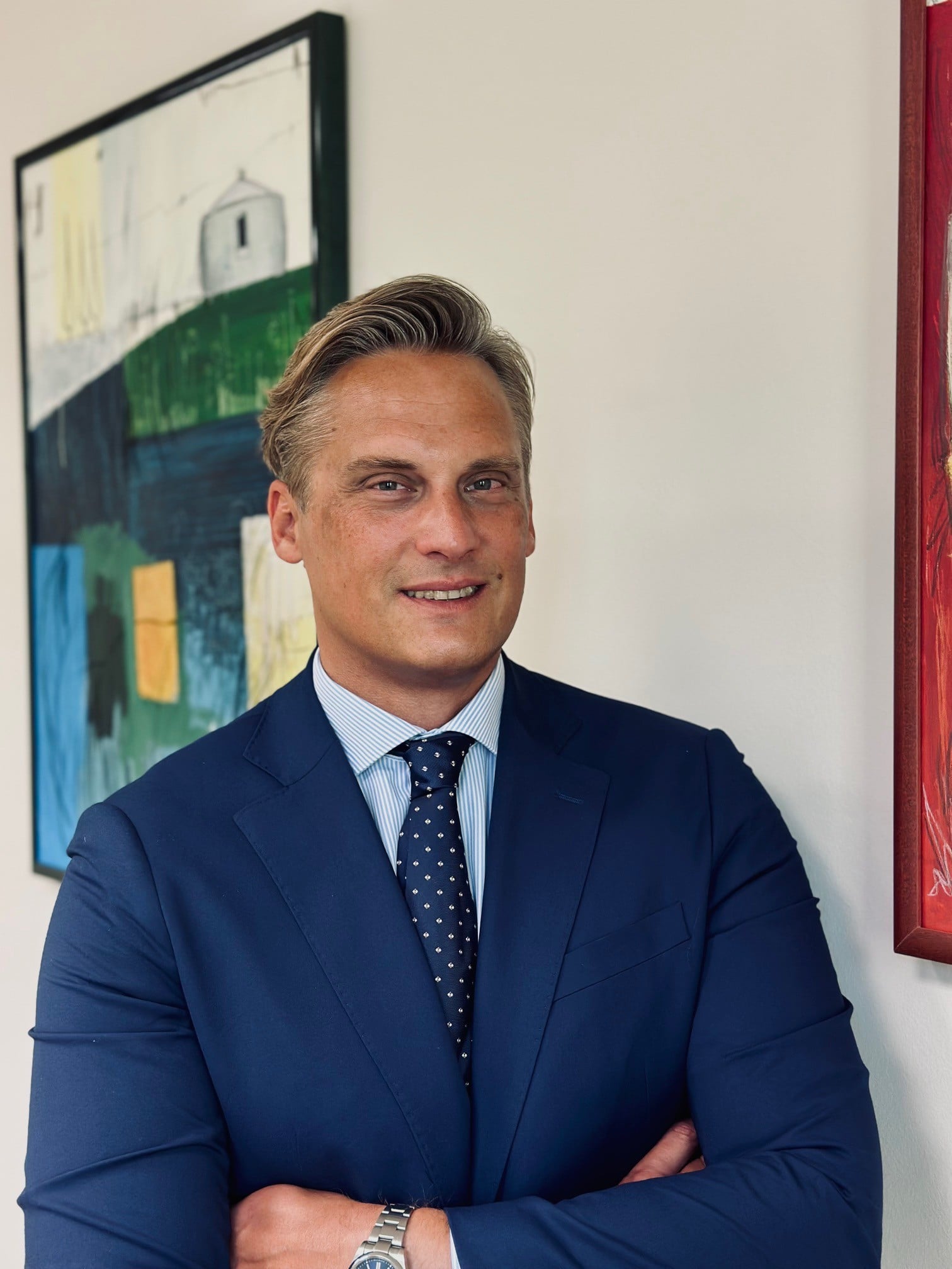 Lawyer posing confidently with arms crossed in a professional setting decorated with abstract art.