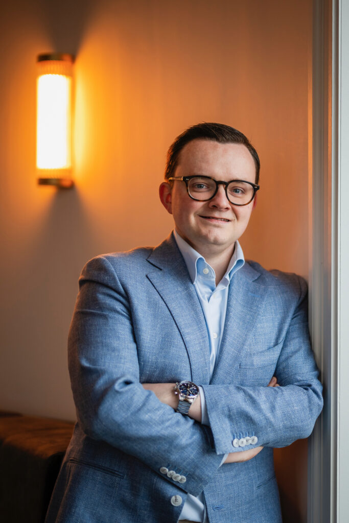 Lawyer posing confidently in a tailored suit, arms crossed, in a well-lit office setting.
