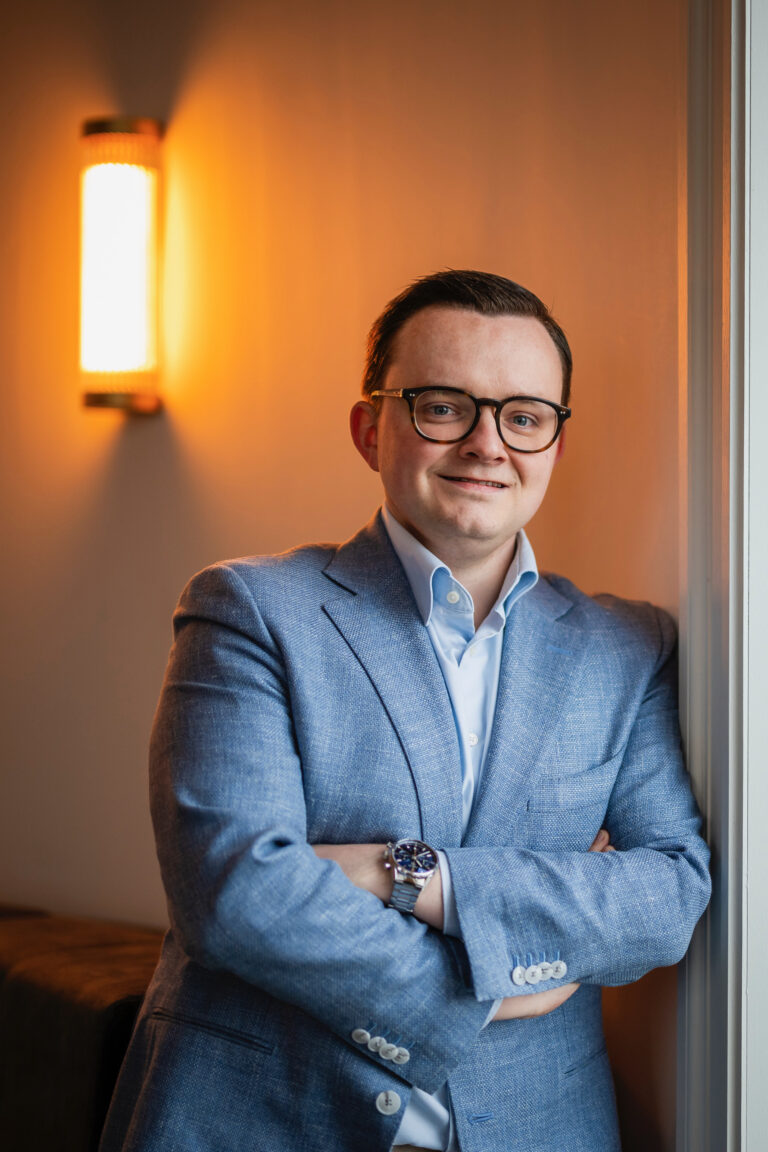 Lawyer posing confidently in a tailored suit, arms crossed, in a well-lit office setting.