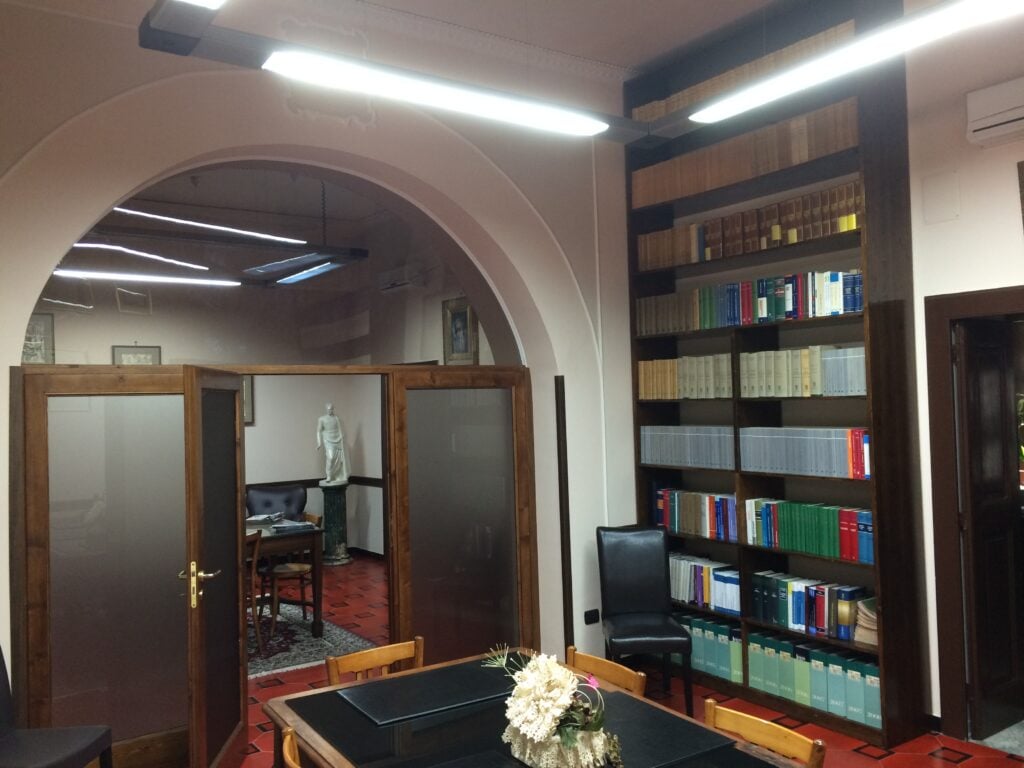 Law office interior featuring a bookshelf filled with legal texts and a table with a flower arrangement.