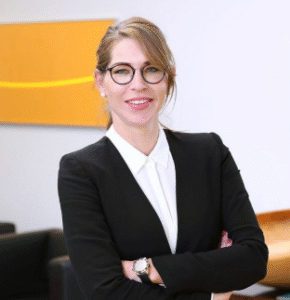 Lawyer standing confidently with arms crossed in modern office setting.