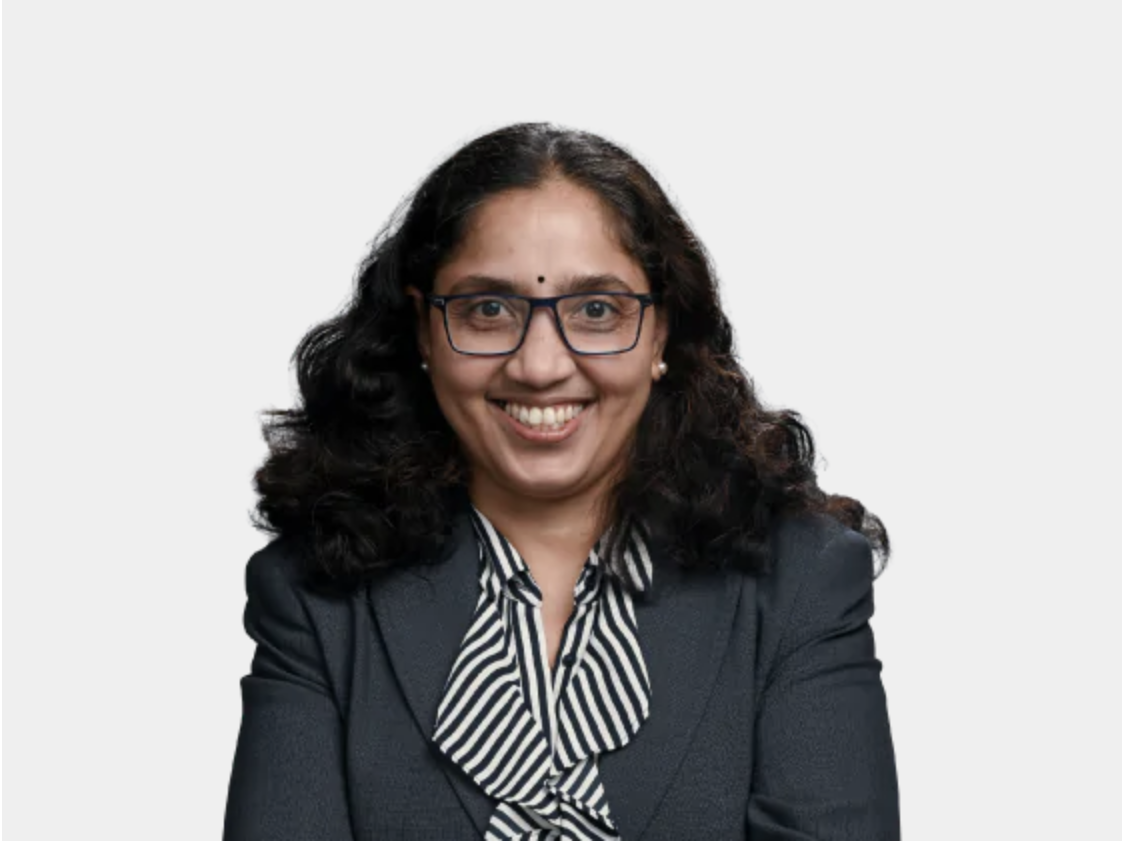 Lawyer smiling while wearing a dark suit and glasses, against a plain background.