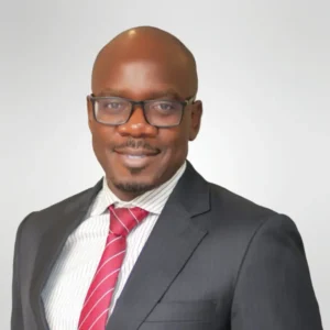 Male attorney in a suit and tie, smiling against a neutral background, representing a professional legal image.