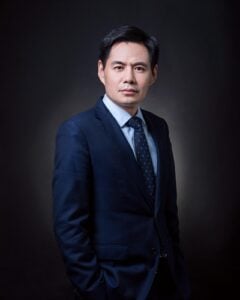 Attorney in a formal suit posing confidently against a dark background for a professional profile.