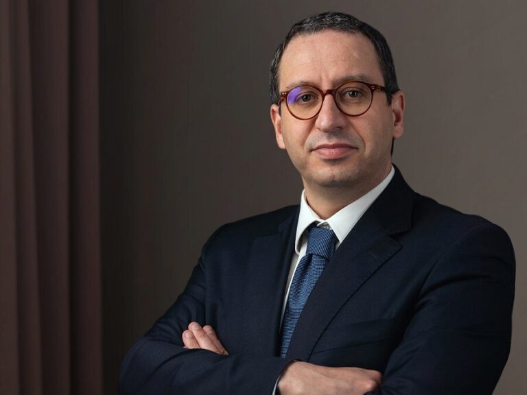 Attorney in suit with arms crossed, posing against a neutral backdrop.