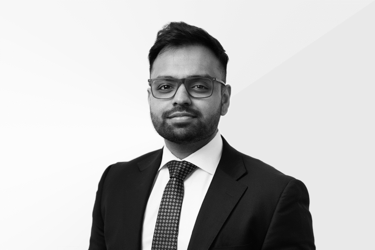 Legal professional wearing glasses and a suit, posing against a light background.