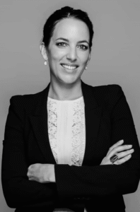 Attorney posing confidently with arms crossed, dressed in a professional suit against a plain background.