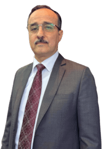 Lawyer in a suit, standing confidently with a neutral expression against a plain background.