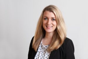 Lawyer posing for a professional portrait with a neutral background, smiling and dressed in business attire.