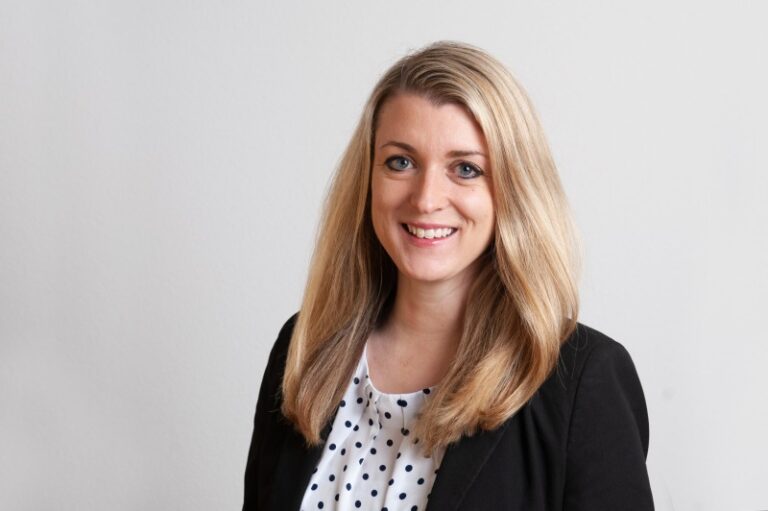 Lawyer posing for a professional portrait with a neutral background, smiling and dressed in business attire.