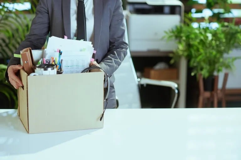 Lawyer carrying a box filled with documents and office supplies in a professional workspace.