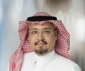 Legal professional wearing traditional attire, smiling against a neutral background.
