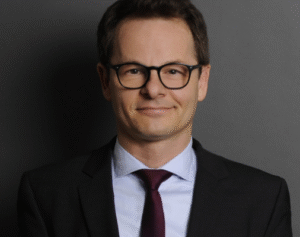 Lawyer in professional attire, smiling, against a plain background.