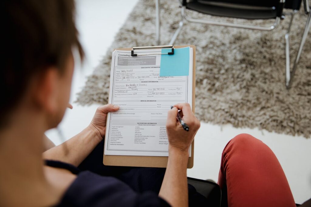 Person filling out a counseling form while seated in a professional office setting.