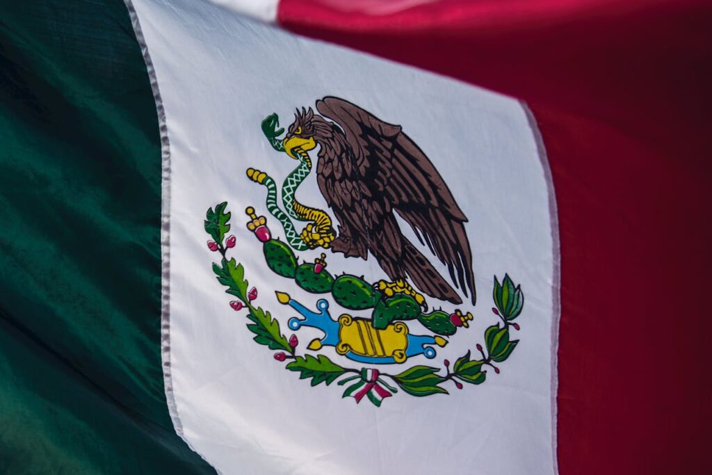Mexican flag with eagle, snake, and cactus in the center, representing national identity and heritage.